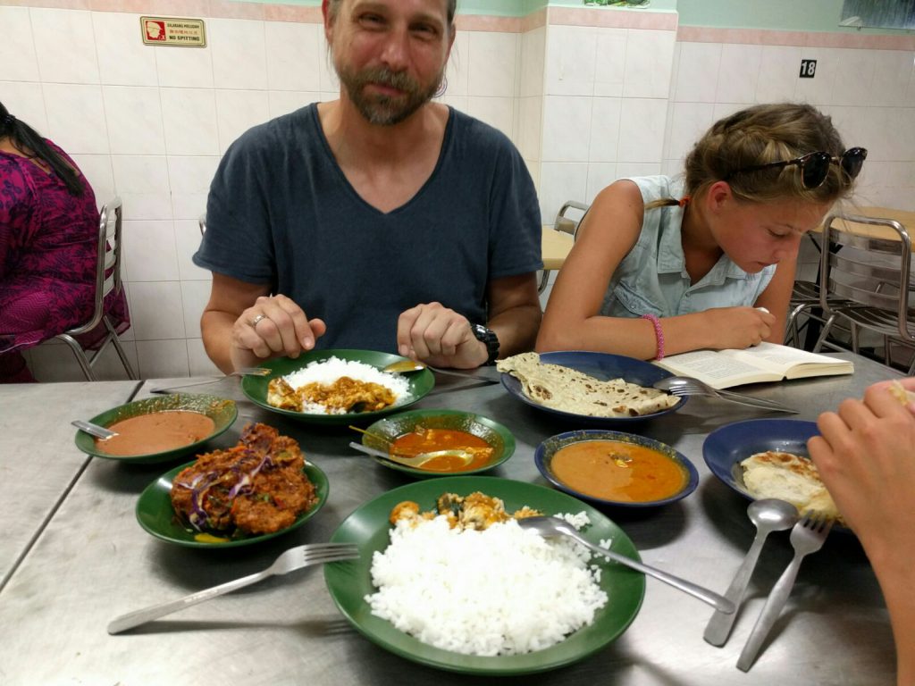 Currysauce, Huhn, Fisch, Reis und Roti Canai beim Indern während Lara, wie die letzten beiden Tage, durchgängig selbst auf dem Weg zum Lokal liest.